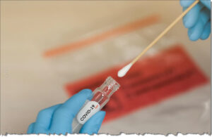 covid test vial and swab held by hands wearing latex gloves